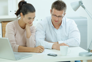 Happy young casual couple sitting at desk working together at home office, smiling. Click here for more "People at Home" images: [url=my_lightbox_contents.php?lightboxID=1507925][img]http://www.nitorphoto.com/istocklightbox/peopleathome.jpg[/img][/url]